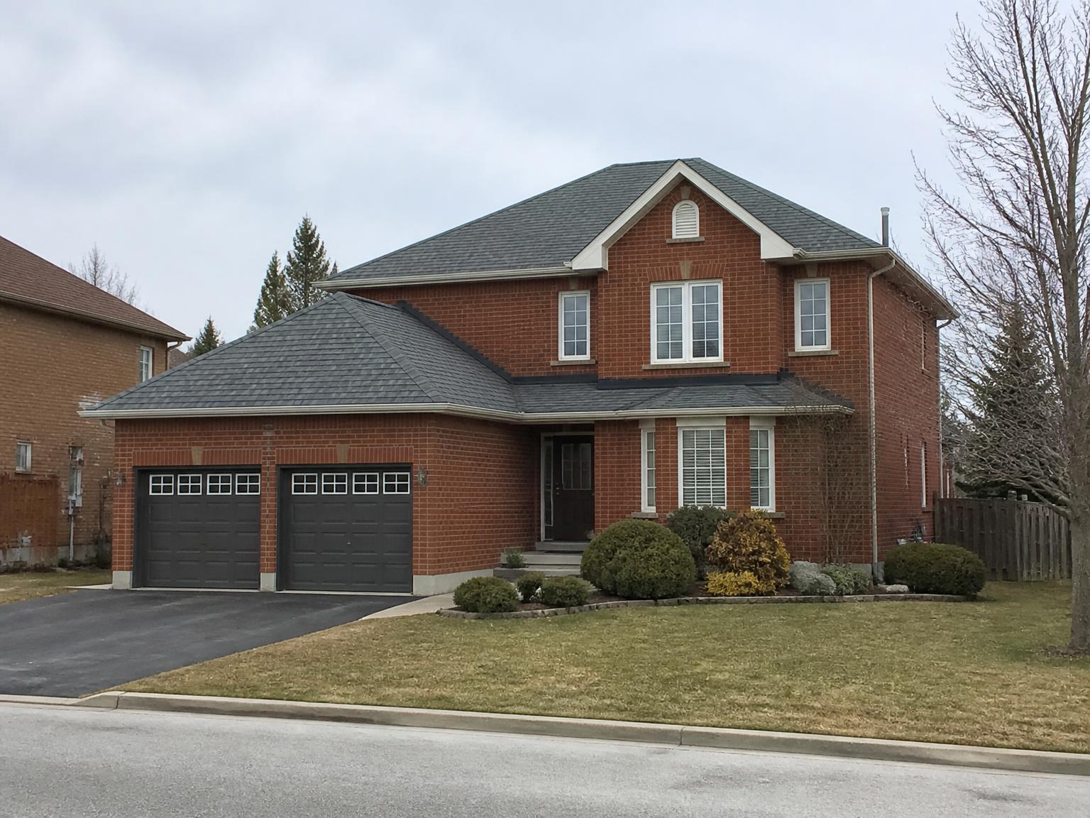 Completed dark grey shingle roof on a suburban brick home in the Greater Toronto Area